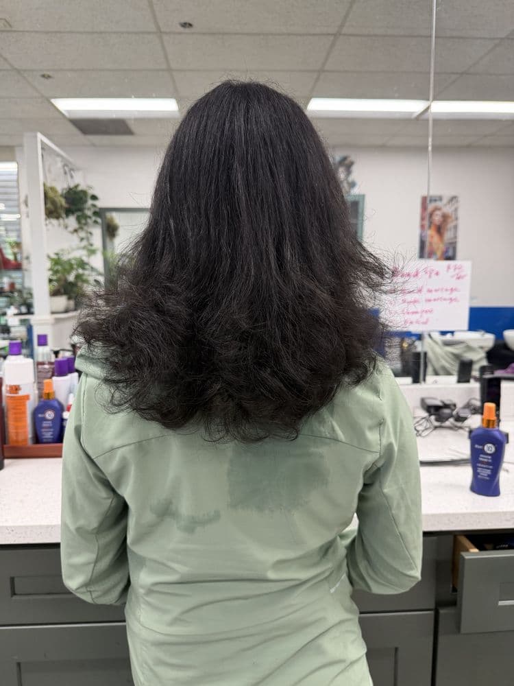 Women's long dark layered haircut with volume at Dimension Hair Salon