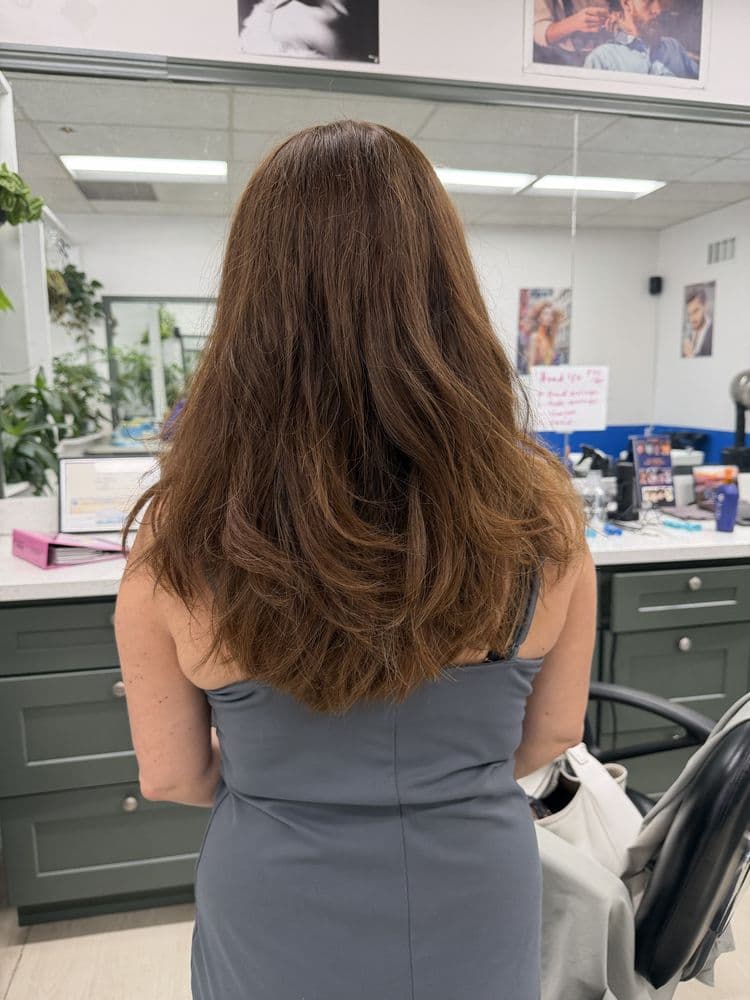 Women's long layered haircut with warm natural color at Dimension Hair Salon