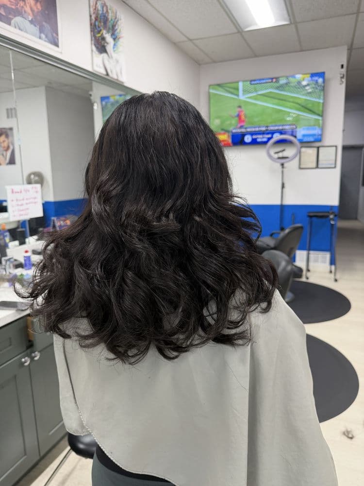 Women's dark layered hairstyle with soft waves at Dimension Hair Salon